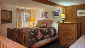 Une chambre confortable avec un lit en bois, une literie à motifs floraux, une commode en bois et une fenêtre avec des rideaux.