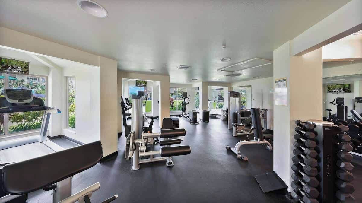 A gym with treadmills, weight machines, and dumbbells.