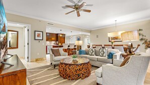 A modern living room with a sofa, armchairs, a coffee table, and a dining area in the background. - Maui Resort Rentals: Honua Kai Konea 749, Premier 7th Floor Penthouse 3BR w/ Gorgeous Ocean and Black Rock Views! (Lahaina)