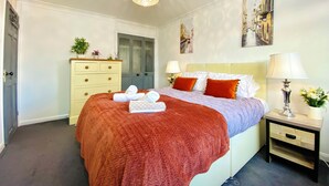 A bedroom with a bed, two bedside tables, a dresser, and a ceiling light fixture. - NEW Modern 4-Bed House, Deluxe Living, 3 Bathrooms (Reading)