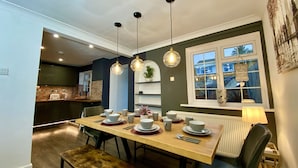 A dining area with a wooden table set for four, a bench, and a window with a view of the outside. - NEW Modern 4-Bed House, Deluxe Living, 3 Bathrooms (Reading)