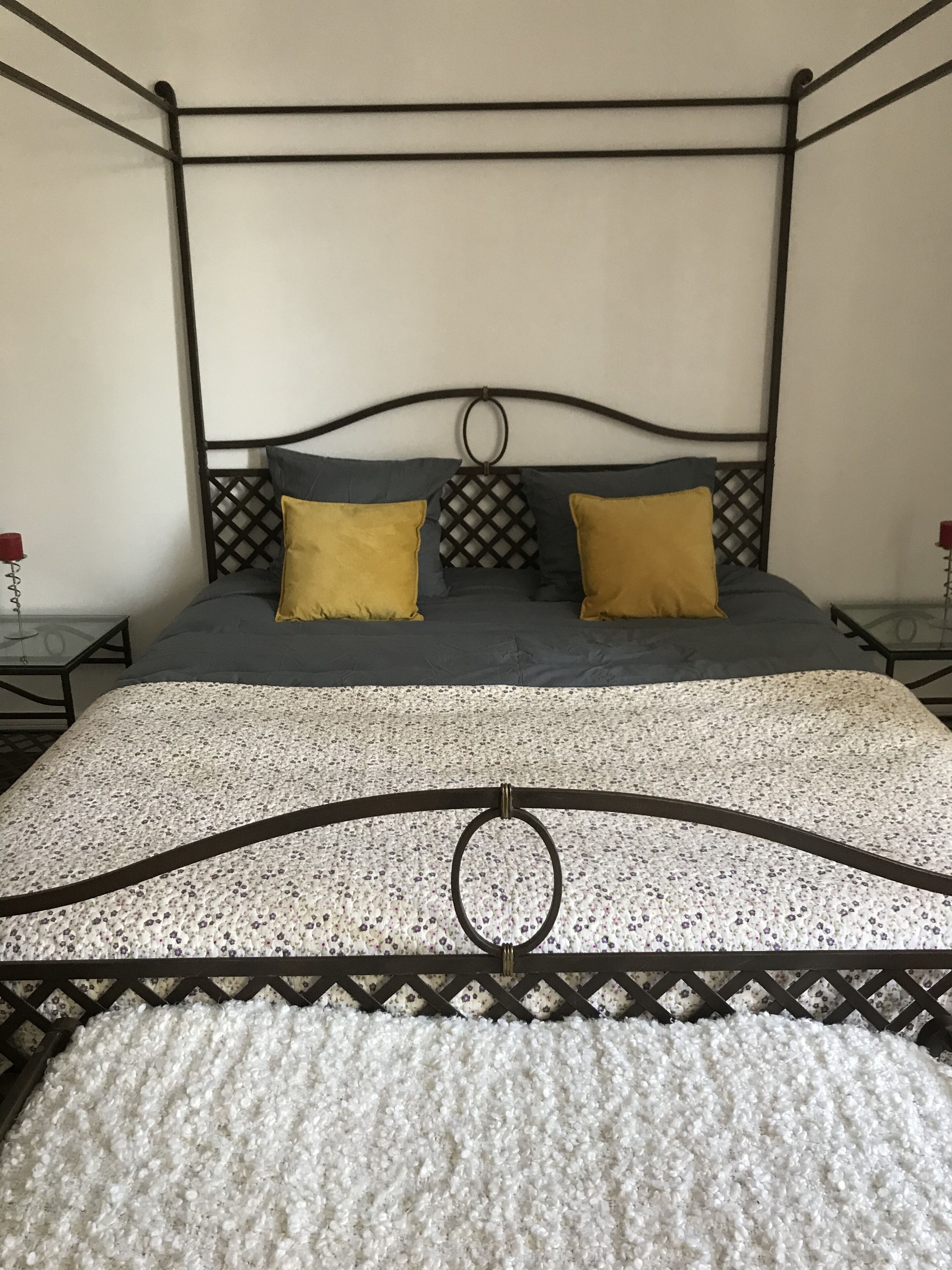 A four-poster bed with a floral-patterned bedspread and two pillows.
