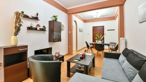 Ein modernes Wohnzimmer mit einer Couch, einem Couchtisch und einem Essbereich mit Tisch und Stühlen. An der Wand befindet sich eine Holzkommode mit Dekoration.