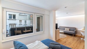 Ett modernt rum med ett stort fönster, en soffa, ett litet bord och en tv.