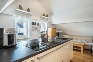 Une cuisine moderne équipée d’une machine à expresso intégrée, d’un évier et d’une fenêtre donnant sur une maison.