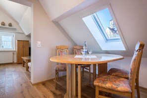 Un área de comedor con una mesa redonda, sillas, una ventana con vistas a un edificio y una puerta.