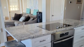 Una cocina moderna con armarios blancos, encimera de granito, electrodomésticos de acero inoxidable y un taburete de bar.