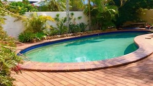 A swimming pool with a brick border, surrounded by greenery and a white wall. - Cotton Tree Tranquil Gem (Maroochydore)