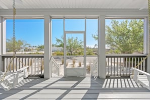 Relax on the covered porch with a swing chair, taking in the serene views of the sandy beach and lush greenery.