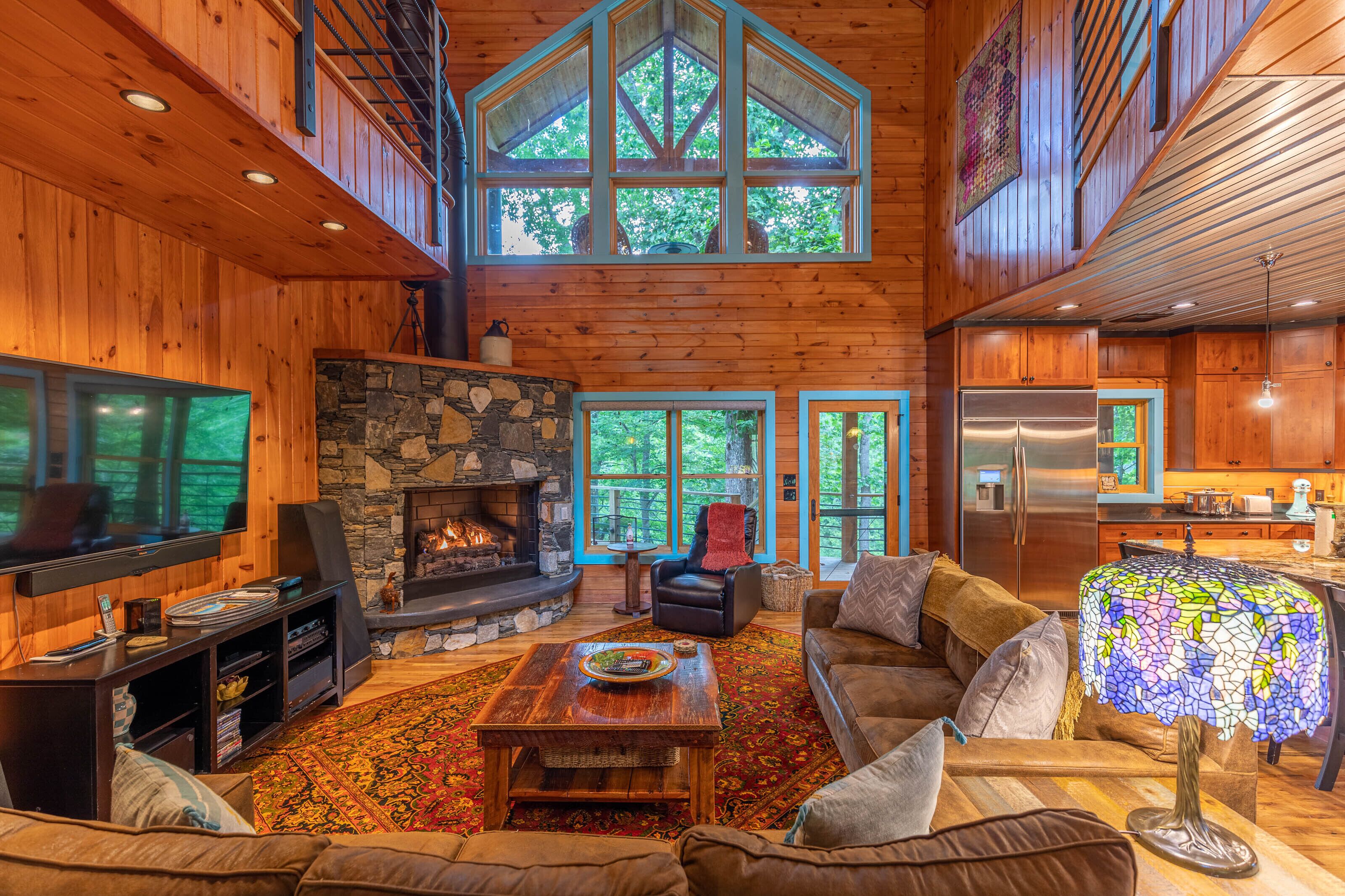 Gather around a roaring fire beneath soaring cathedral ceilings, with treetop views pouring in through towering windows.