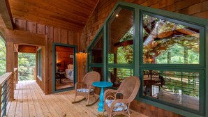 Una baita di legno con veranda, sedie a dondolo e un tavolo.