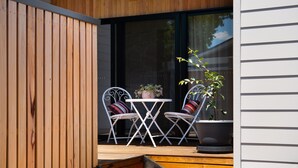 Un espace extérieur aménagé avec deux chaises et une table, un pot de fleurs et une terrasse en bois.