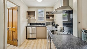 Een compacte keuken met ingebouwde apparatuur, een magnetron en een fornuis.