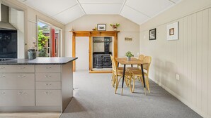 Een keuken met een centraal eiland, houten kastjes en een eethoek met stoelen.