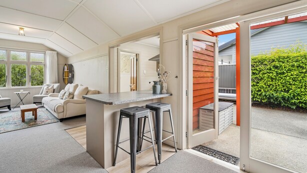 Een moderne keuken met een bar, een zithoek met een bank en stoelen, en uitzicht op de achtertuin.