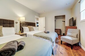 Una habitación de hotel con dos camas, una silla, un televisor y un armario.