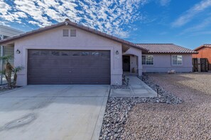A residential house with a garage, a driveway, and a gravel area.