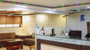 A reception area with a reception desk, seating area, and a wall with a geometric pattern. - Hotel Mukesh residency (Pune)
