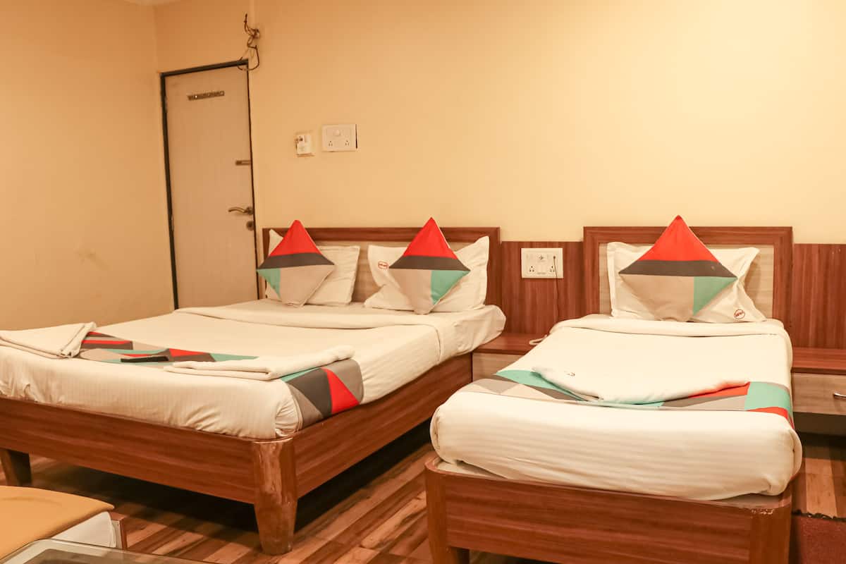 Two wooden beds with white bedding and geometric pillows, a wooden nightstand, and a door.
