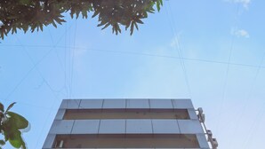 A multi-story building with a flat facade, multiple windows, and visible electrical wiring. - Hotel Mukesh residency (Pune)