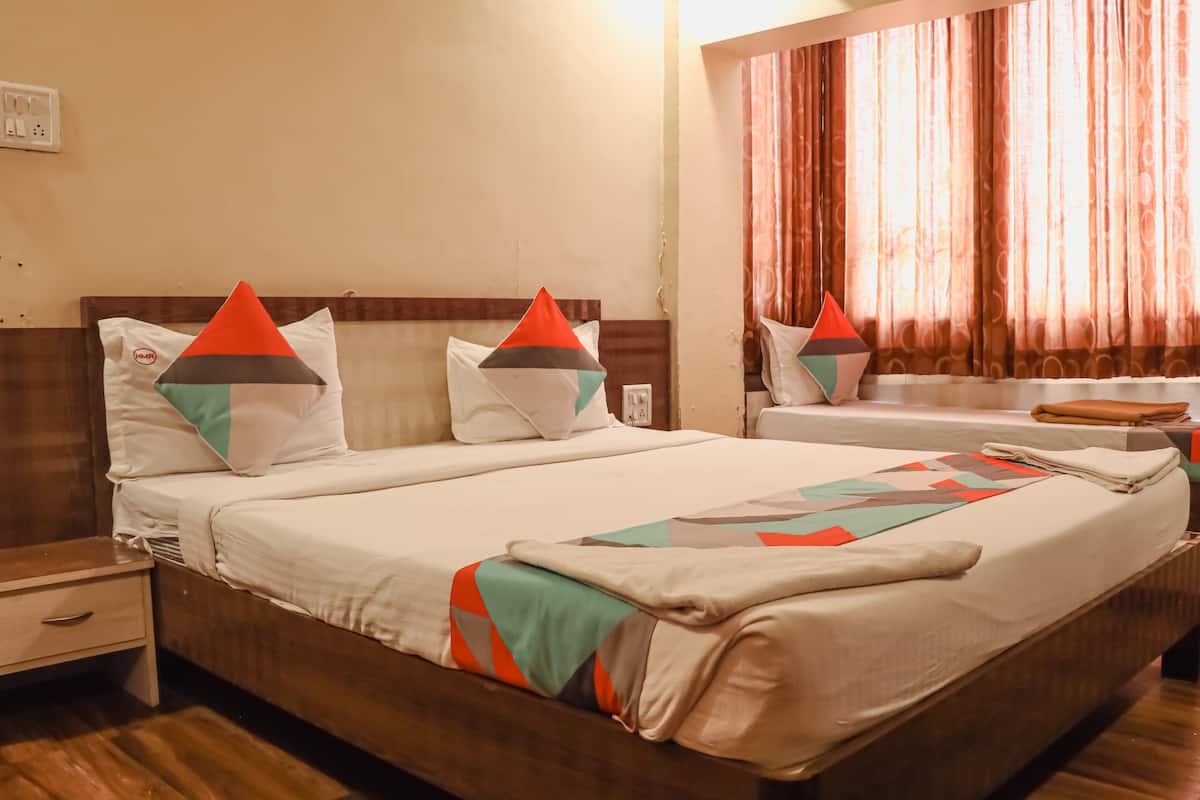 A double bed with a wooden headboard, a nightstand, and a window with curtains.