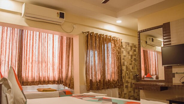 A hotel room with two beds, a desk, a mirror, and an air conditioning unit. - Hotel Mukesh residency (Pune)