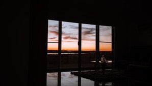 Huone, jossa on suuri ikkuna, josta avautuu näkymä auringonlaskuun.