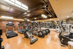 A gym with various cardio machines, mirrors, and exercise equipment.
