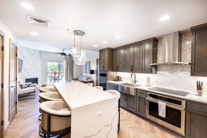A modern kitchen with a marble island, stainless steel appliances, and dark wood cabinets. - Westgate 3303A (Park City)