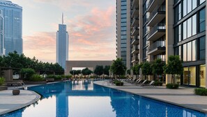 A modern hotel with a swimming pool, surrounded by lush greenery and high-rise buildings. - Dream Inn Apartment- Boulevard Heights (Dubai)