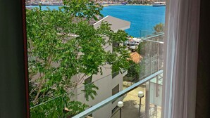 A balcony with a clear view of a coastal town, a body of water, and a hilly landscape. - Sahil Otel (Cesme)