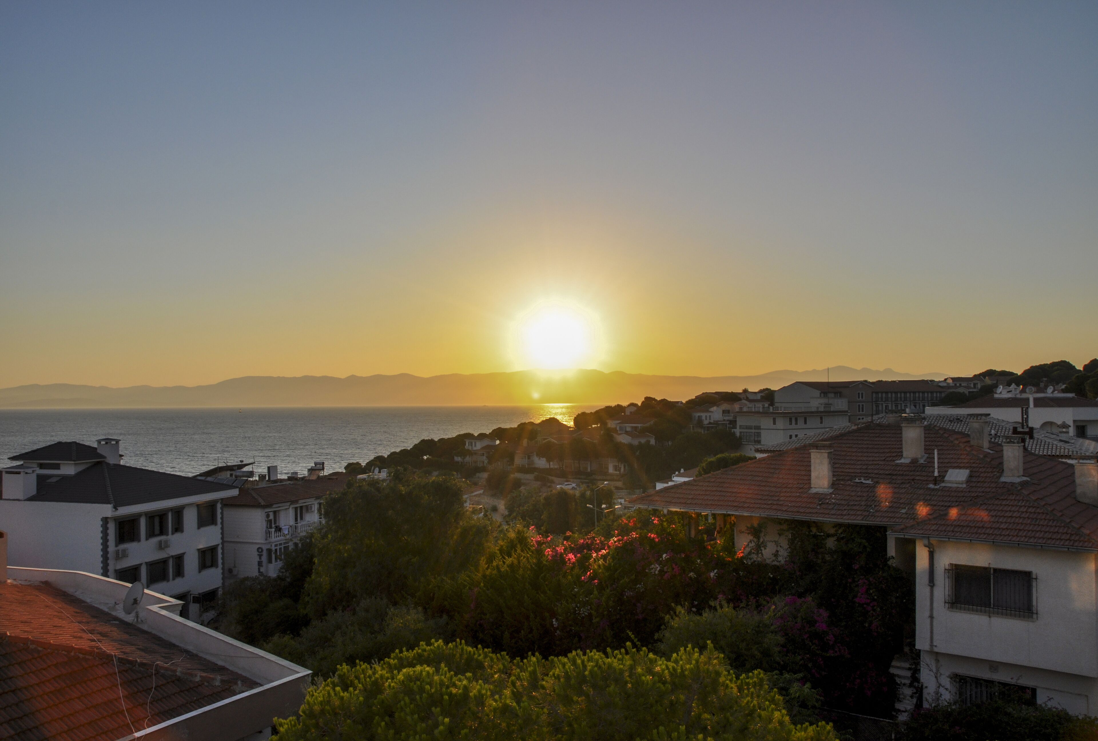 Zona residencial costera con casas y vista al mar durante el atardecer.