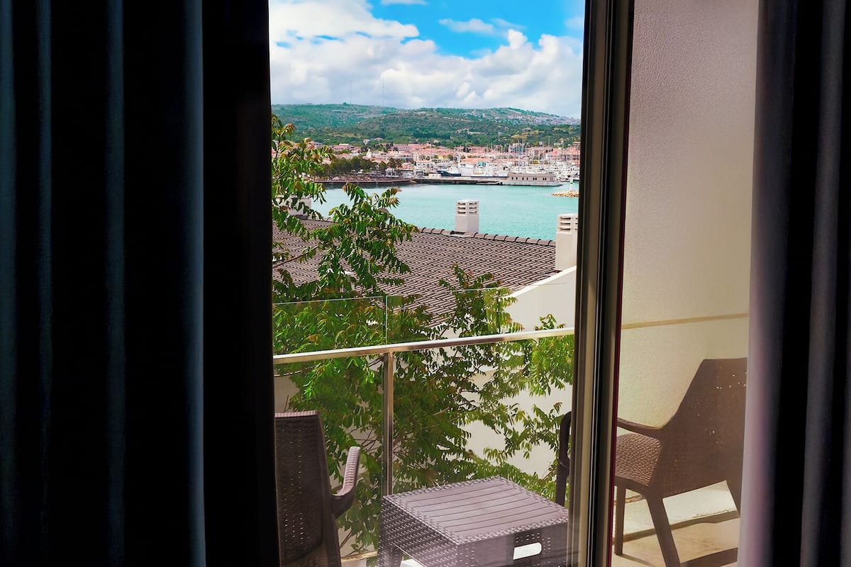 A balcony with a view of a marina and a hilly landscape.