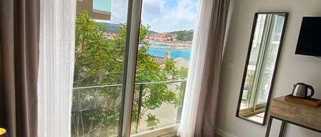 Habitación de hotel con una cama grande, un televisor, un espejo y vistas a la costa.