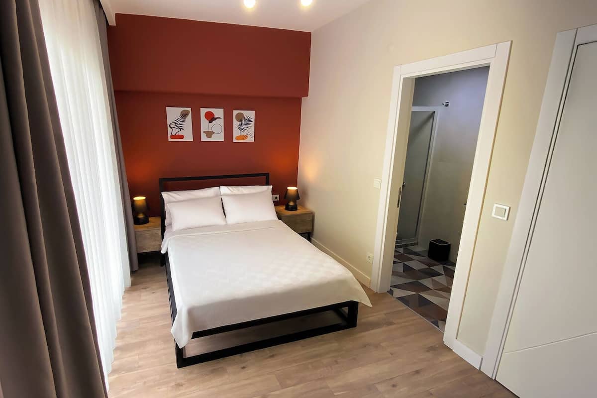 A bedroom with a bed, nightstands, and wall art.