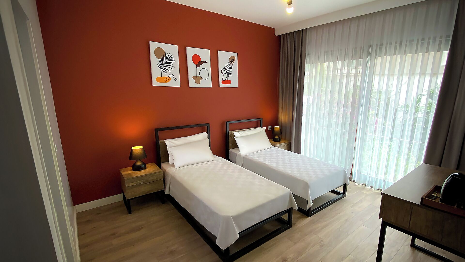Habitación de hotel con dos camas, un escritorio y una ventana con cortinas.