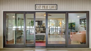 Une entrée moderne avec une porte en verre, un ventilateur de plafond et une enseigne sur laquelle on peut lire : « MANGE, PRIE, AIME ».