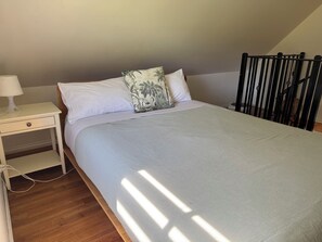 A bedroom with a bed, a nightstand, a lamp, and a window with natural light. - "Experience the ultimate retreat surrounded by the untouched beauty of nature.  (Erica)