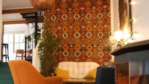 A living room with a patterned wall, a sofa, two chairs, a hanging light fixture, and a fireplace. - "Experience the ultimate retreat surrounded by the untouched beauty of nature.  (Erica)