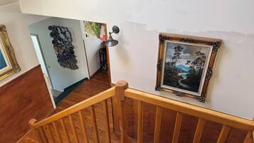Eine Holztreppe mit Geländer, ein gerahmtes Gemälde an der Wand und ein dekorativer Wandbehang.