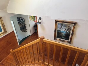Uma escada de madeira com corrimão, um quadro emoldurado na parede e um enfeite de parede decorativo.