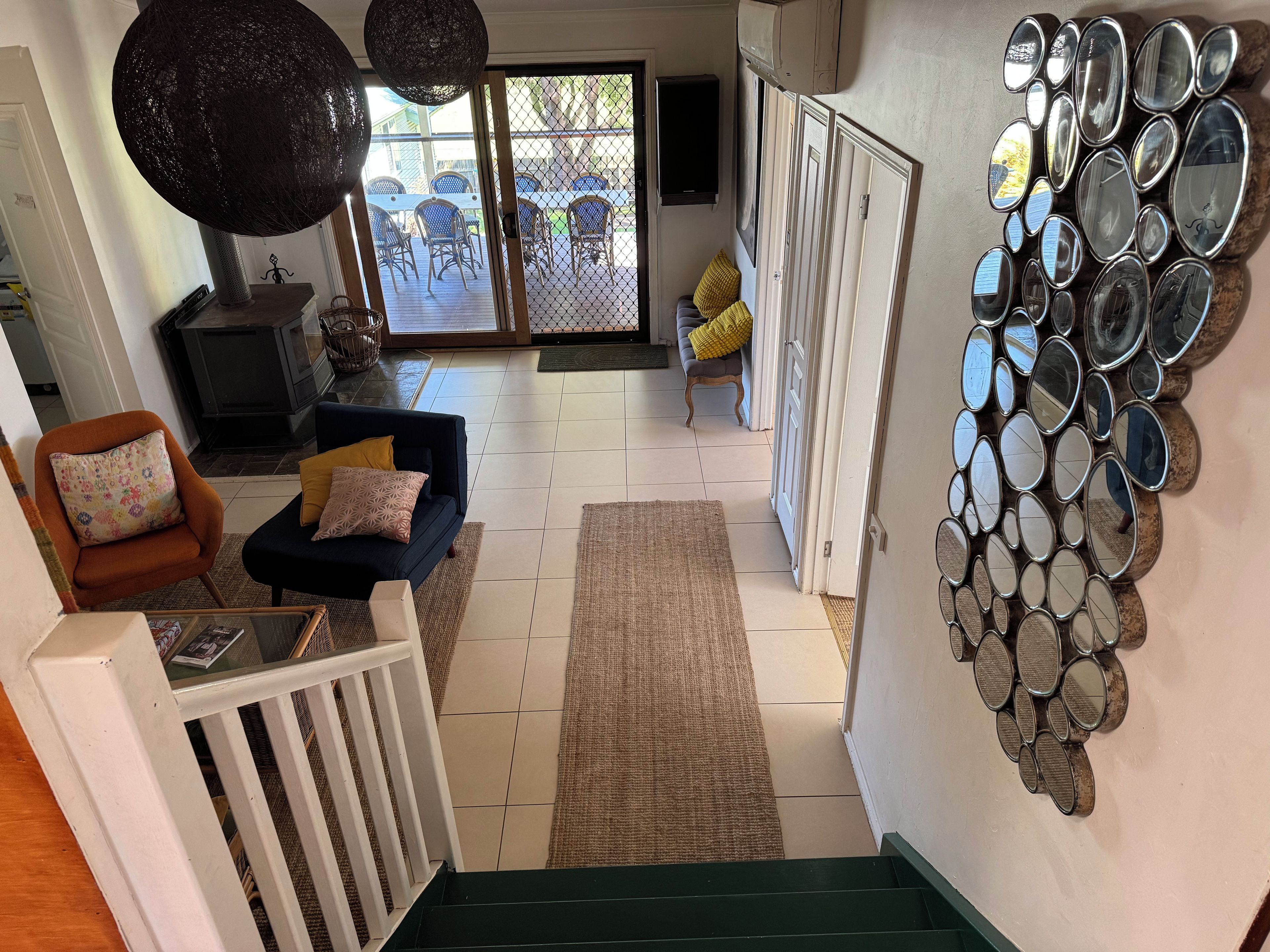 A staircase leading to a living area with a view of outdoor furniture and a wall with circular mirrors.