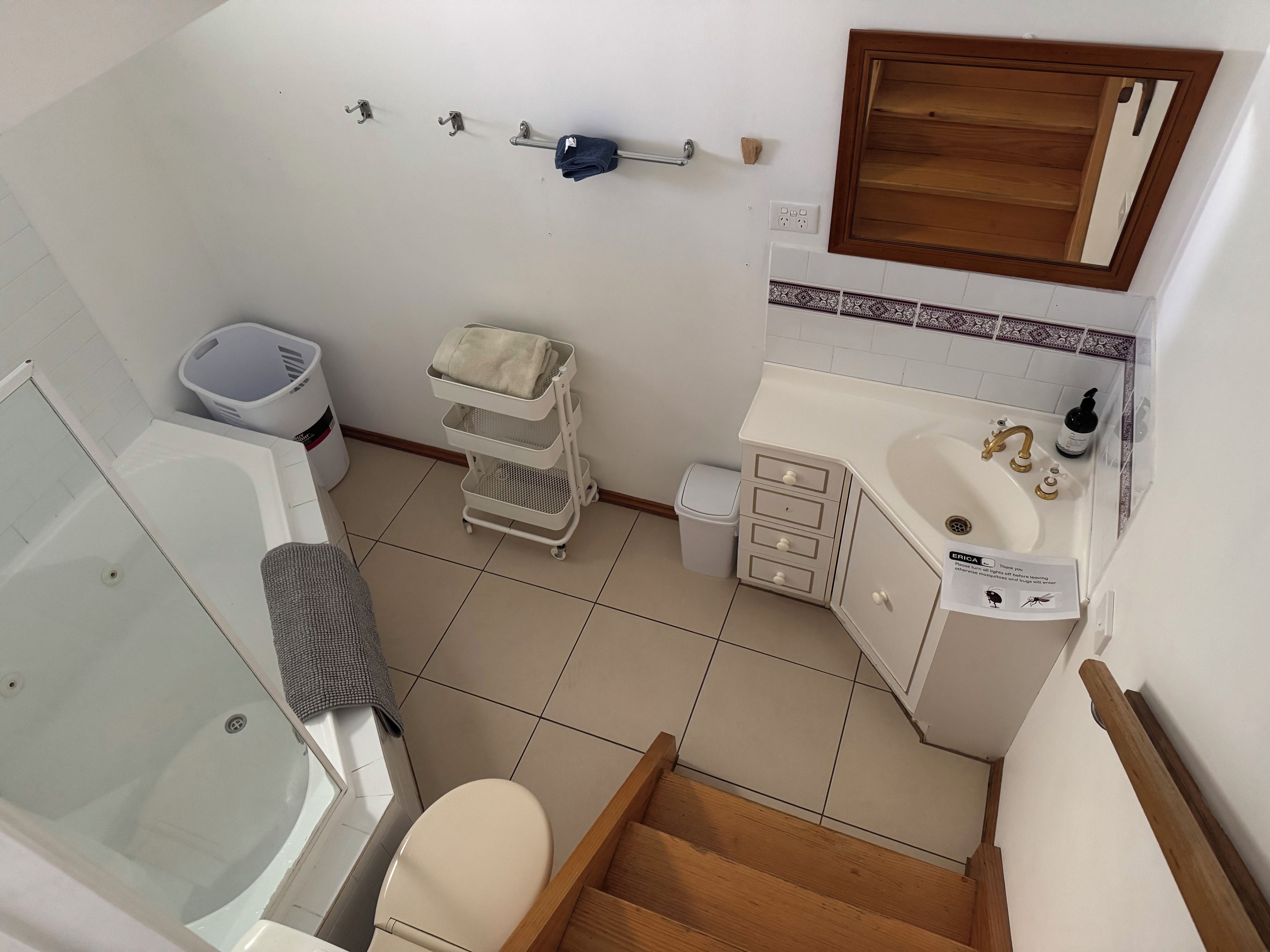 A bathroom with a bathtub, toilet, sink, and a small laundry basket.