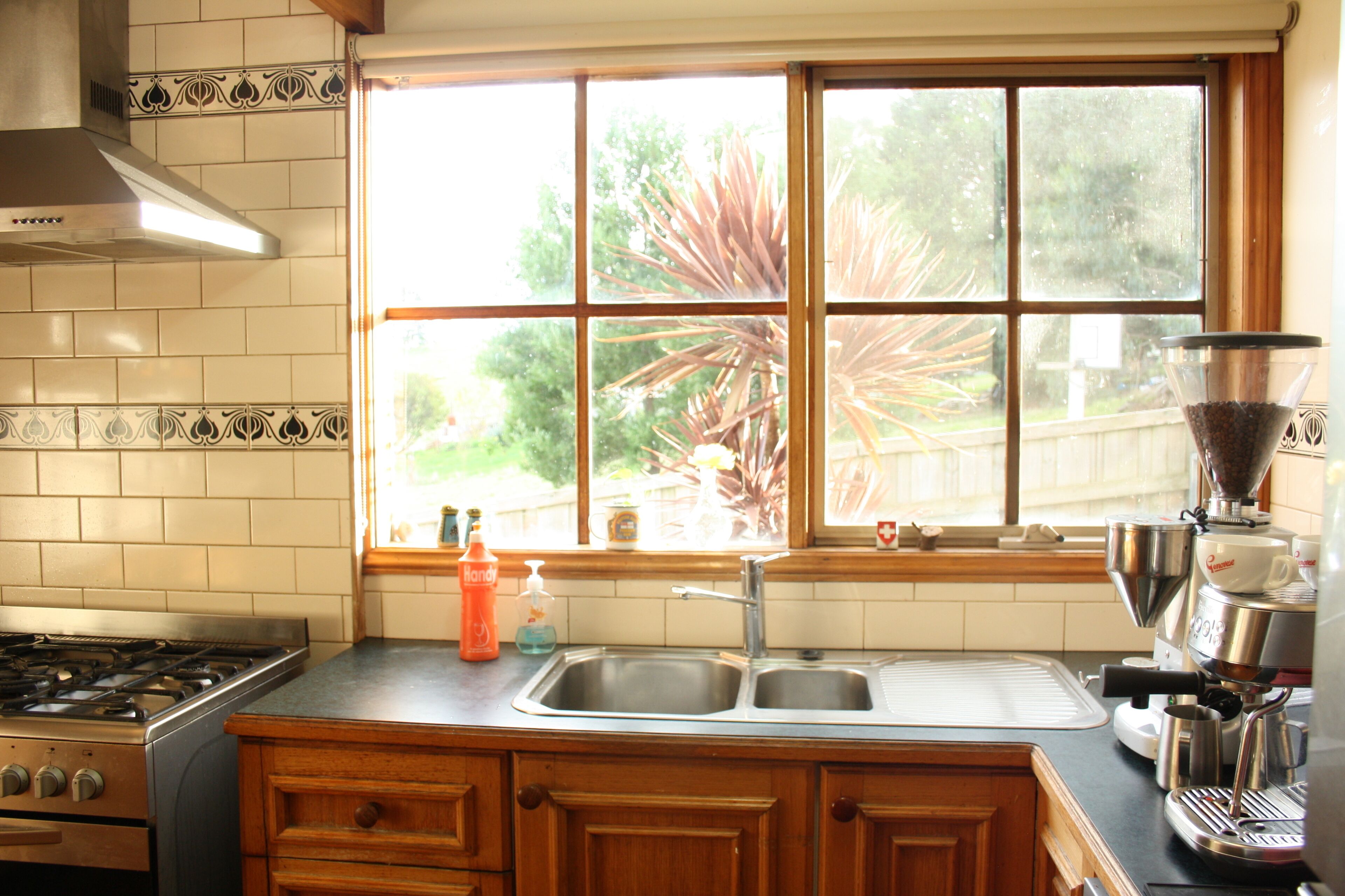 A kitchen with a stove, sink, and window overlooking a garden.