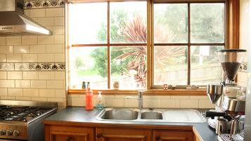 A kitchen with a stove, sink, and window overlooking a garden.
