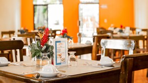 A restaurant interior with tables set for dining, a menu stand, and a decorative plant centerpiece.