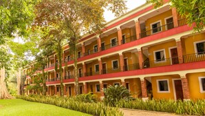 A multi-story hotel with balconies, a well-maintained lawn, and a brick facade.