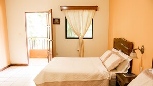 A hotel room with a bed, a nightstand, a lamp, and a window with curtains.