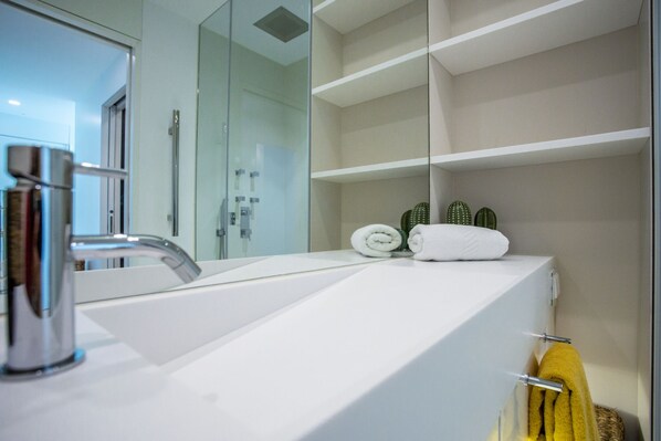 A modern bathroom with a large mirror, a white sink, and a glass shower enclosure.