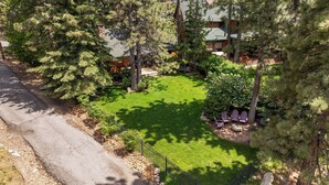 A residential property with a well-maintained lawn, a stone fireplace, and a wooden deck.